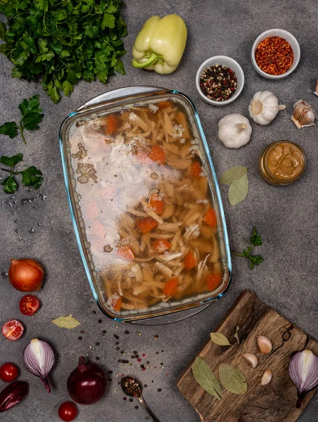 Homemade jelly with meat. Aspic poultry and beef, traditional Russian and Ukrainian dish on a gray background with mustard, spices and different ingredients. Holodets