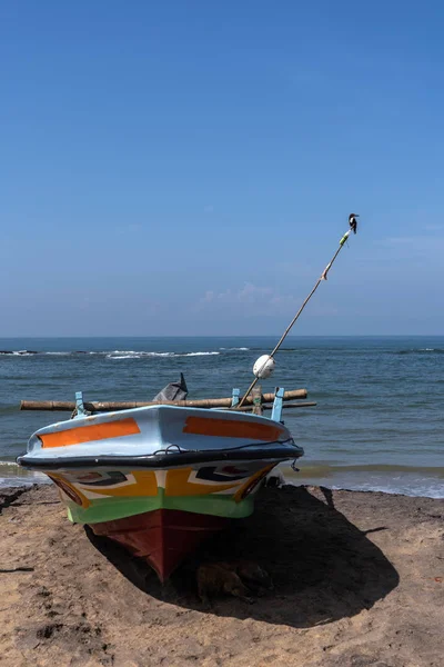 Fishing boat stands on the ocean beach. The Kingfisher bird sitting on a homemade fishing lighthouse on fishing boat. — Stock Photo, Image