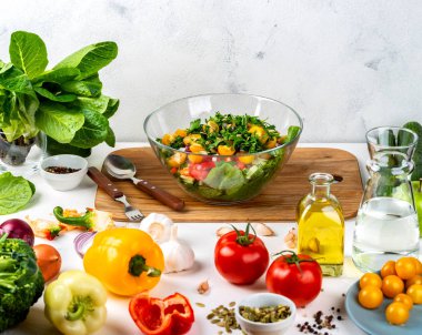 Farklı ekolojik sebzelerden alınmış bir kase dolusu salata ve masada baharatlar. Sağlıklı beslenme konsepti.