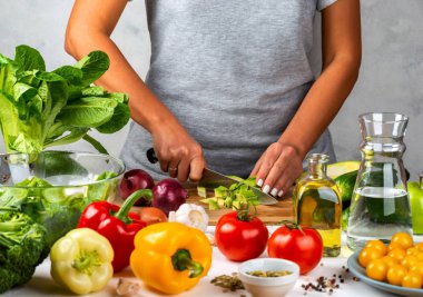 Kadın avokado keser ve mutfakta salata pişirir. Sağlıklı diyet kavramı.