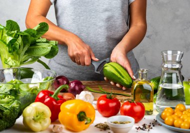 Kadın avokado soyuyor, mutfakta salata pişiriyor. Sağlıklı diyet kavramı.