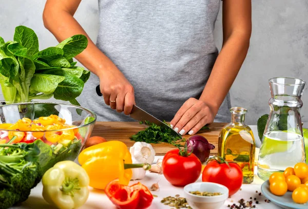 A nő zöldséget vág és salátát főz a konyhában. Egészséges táplálkozás koncepciója. — Stock Fotó