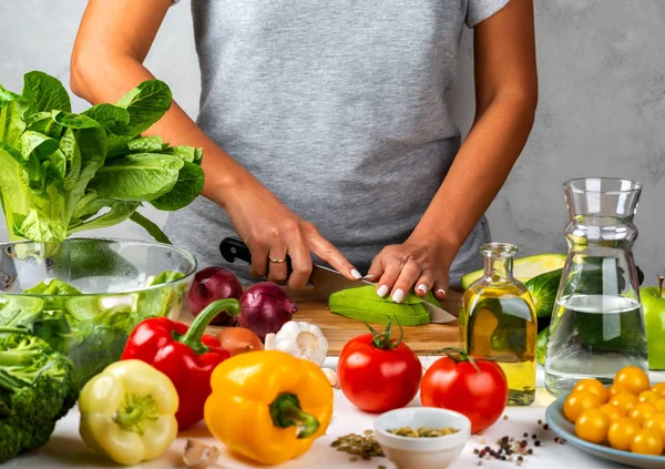 Una donna taglia l'avocado e cucina insalata in cucina. Dieta sana concetto . — Foto Stock