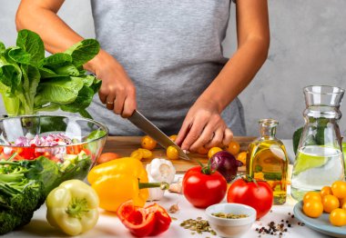 Kadın mutfakta sarı kiraz domatesleri ve salata pişiriyor. Sağlıklı diyet kavramı.