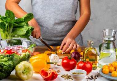 Kadın mutfakta sarı kiraz domatesleri ve salata pişiriyor. Sağlıklı diyet kavramı.