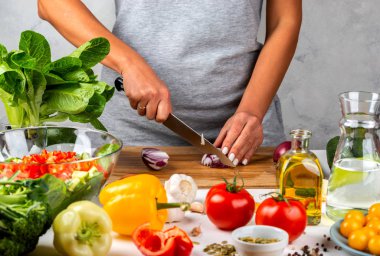 Kadın soğan doğruyor ve mutfakta salata yapıyor. Sağlıklı diyet kavramı.