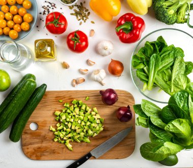 Tahtada dilimlenmiş avokado ve masada farklı sebzeler. Salata malzemeleri. Sağlıklı beslenme konsepti. Üst görünüm.