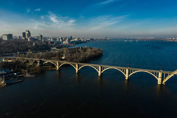 Letecký panoramatický výhled na starý obloukový most Merefo-Cherson přes řeku Dněpru v Dněpropetrovsku. Pohled na pravý břeh města Dnipro. — Stock fotografie