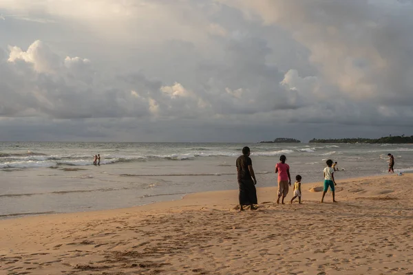 Hikkaduwa, Sri Lanka, November, 2019: Young parents and their children walk along the beach. — Stock Photo, Image