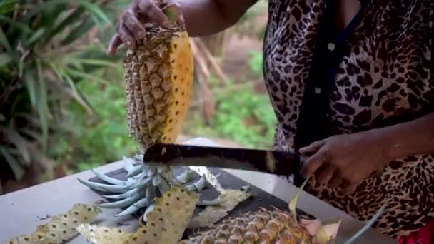 Kvinna peeling ananas med en stor kniv på bordet — Stockvideo