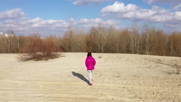 Dziewczyna w jasnej zimowej kurtce spaceruje po plaży — Wideo stockowe