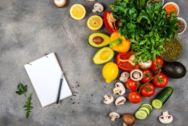 Different vegetables and ingredients for cooking delicious dishes. A book for writing recipes lies on the table. Copy space for text