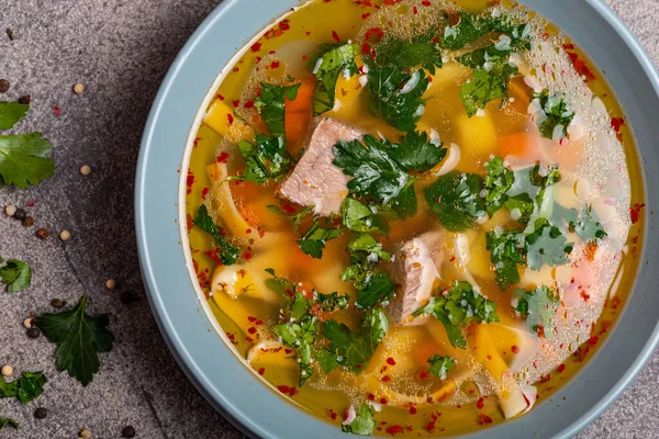 Köstliche würzige Suppe mit Rindfleisch und Nudeln auf grauem Hintergrund. Ansicht von oben. Makro — Stockfoto