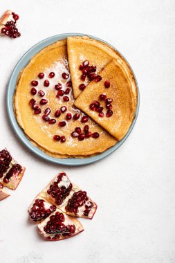Nar ve yoğunlaştırılmış sütle kaplı krepler bir tabakta yatar. Yakın plan. Uzayı metin için kopyala. Üst görünüm.
