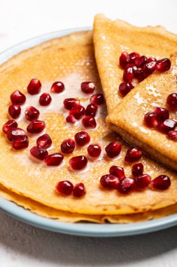 Nar ve yoğunlaştırılmış sütle kaplı krepler bir tabakta yatar. Makro. Üst görünüm.