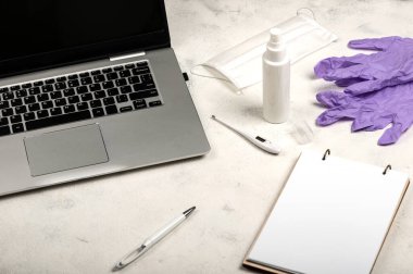 Çevrimiçi iş ve eğitim için karantina koşulları. Evde kal. Laptop, defter, kalem, cerrahi maske, el dezenfektanı ve beyaz arka planda dijital termometre. Sosyal izolasyon