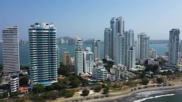 Tráfego urbano perto de arranha-céus modernos, apartamentos de negócios, hotéis em Cartagena, Colômbia. Panning horizontal. Movimento da câmera de baixo para cima . — Vídeo de Stock