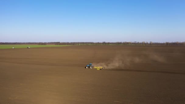 Letecký pohled na pěstování strnišť po sklizni s velkým modrým moderním traktorem agregovaným s vybavením. — Stock video