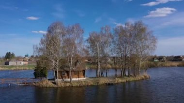 Göl kıyısındaki eve giden köprüyle doğal manzaranın havadan görüntüsü. Gölün ortasındaki bir adada ahşap bir balıkçı evi. Eski Solotvino Köyü, Ukrayna