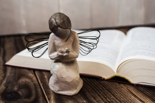 Angel and bible on wooden background — Stock Photo, Image