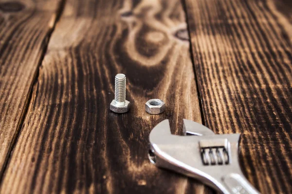 Una llave y un perno con tuerca sobre fondo de madera —  Fotos de Stock