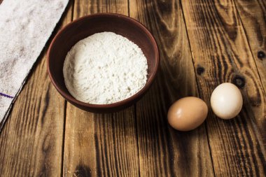 Bir kasede un ve ahşap arka plan üzerinde iki yumurta