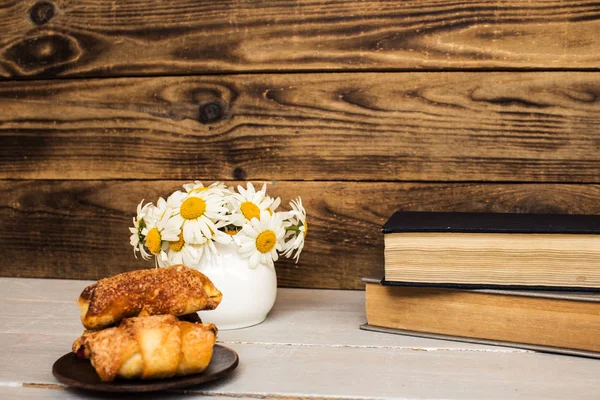 Bouquet of white daisies and books croissants on wood — Stock Photo, Image