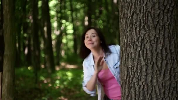 jeune femme agitant derrière un arbre dans la forêt 