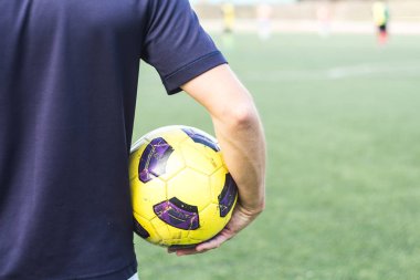 sahada bir futbol topu tutan adam