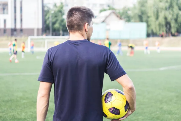 sahada bir futbol topu tutan adam