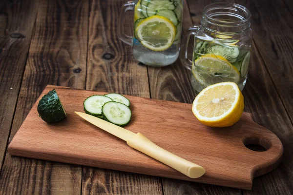 Bir kesme tahtası ve arka planda bir kavanoz salatalık ve limon dilimleri