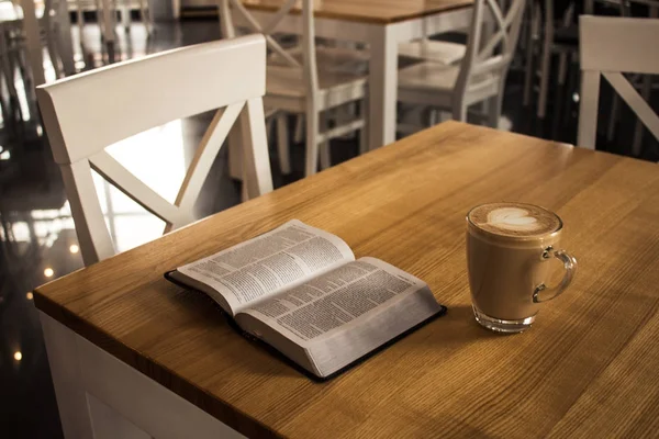 Open bible and a cup of cappuccino — Stock Photo, Image