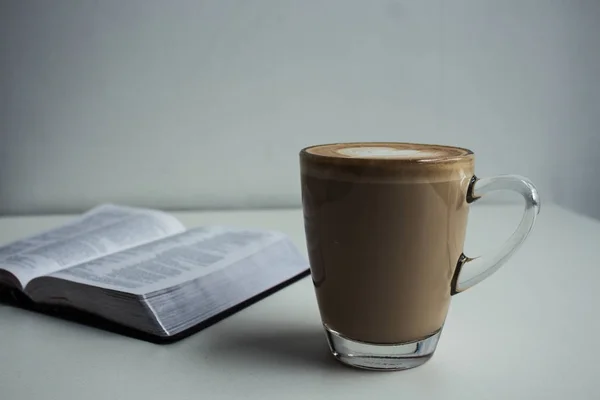 Open bible and a cup of cappuccino — Stock Photo, Image