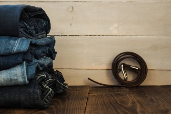 Una pila de jeans sobre un fondo de madera y un cinturón — Foto de Stock