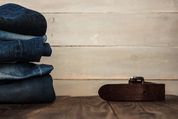 Una pila de jeans sobre un fondo de madera y un cinturón — Foto de Stock
