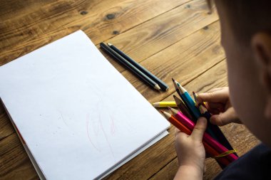 küçük çocuk renkli kalemler tutar