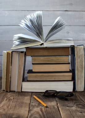 bir yığın kitap üzerine kitap açık gözlük ve kalem ile