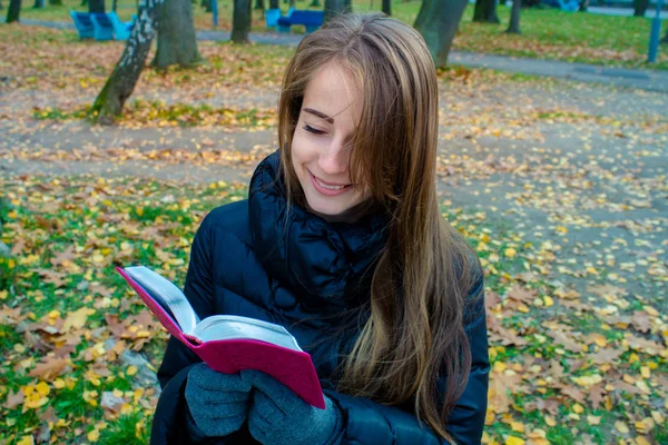 Hermosa chica está leyendo un libro en el parque —  Fotos de Stock