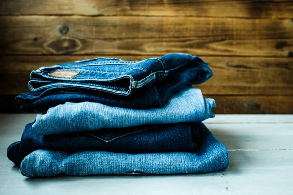 Pila de jeans sobre un fondo de madera — Foto de Stock