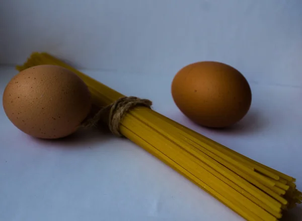 밧줄과 흰색 바탕에 계란과 스파게티 — 스톡 사진