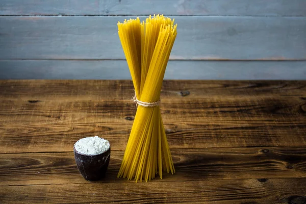 Spaghetti and flour on wooden background — Stock Photo, Image