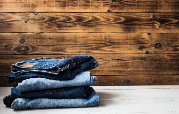 Pila de jeans sobre un fondo de madera — Foto de Stock