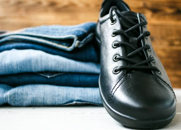 Zapatos en una pila de jeans sobre un fondo de madera — Foto de Stock