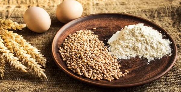 Huevos de harina de trigo y espiguillas de trigo sobre fondo de saco —  Fotos de Stock