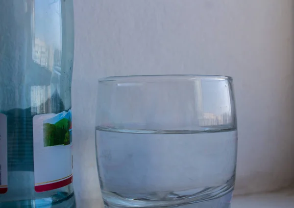 Vaso de agua y botella sobre fondo blanco — Foto de Stock