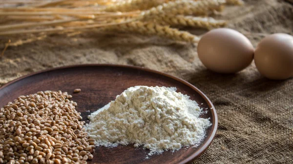 Huevos de harina de trigo y espiguillas de trigo sobre fondo de saco —  Fotos de Stock