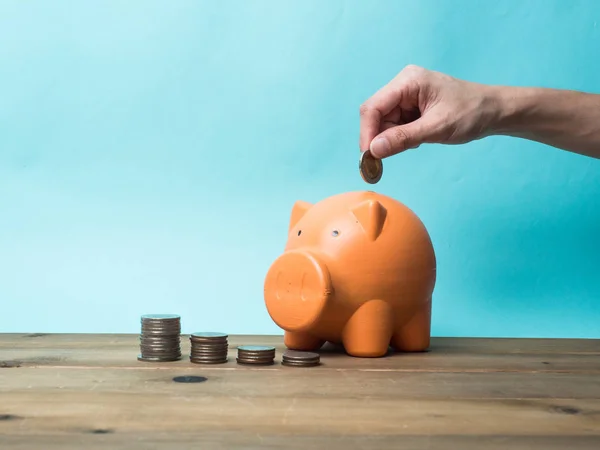 Woman Hand  putting coin into piggy bank for saving with pile of — Stock Photo, Image