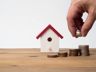 Kırmızı house ile ahşap arka plan üzerinde büyüyen para sikke yığını.