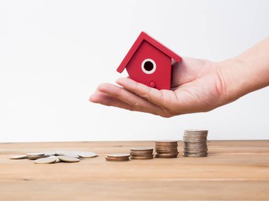 Kırmızı house ile ahşap arka plan üzerinde büyüyen para sikke yığını. 