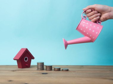 Kırmızı house ile ahşap arka plan üzerinde büyüyen para sikke yığını. 